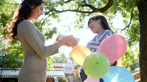 Emotionen-im-sonnigen-Tag,-fröhliche-Frau-mit-bunten-Luftballons-gratuliert-Freund-alles-Gute-zum-Geburtstag-im-park