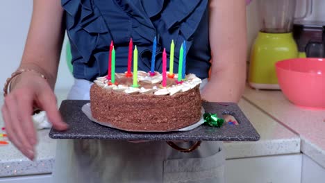 Female-standing-in-kitchen-and-holding-birthday-cake