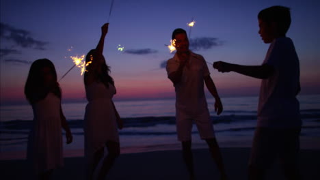 Hispanic-family-celebrating-birthday-with-sparklers-on-beach