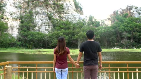 Mann-und-Frau-oder-paar-gehen-Hand-in-Hand-gemeinsam-in-der-Natur-mit-Berg-und-Fluss.-Glücklich-Freiheit-und-Reise-Konzept.