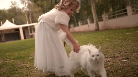 Happy-flower-girl-holding-basket-and-petting-cat-at-wedding