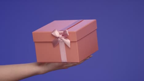 Womans-Hand-hält-eine-schöne-Geschenk-Box-auf-Bluescreen;-Feier-Konzept