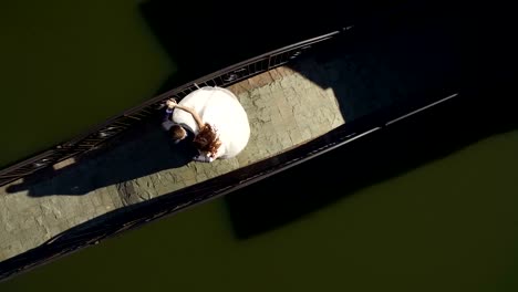 Aerial-view-on-top.-Happy-brides-are-on-a-sunny-day-on-a-bridge-near-the-lake