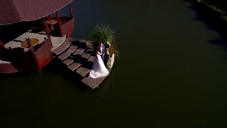 Vista-aérea.-Felices-son-las-novias-en-un-día-soleado-en-un-puente-cerca-del-lago