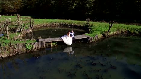 The-brides-sit-near-the-lake-on-a-small-bridge-in-the-park