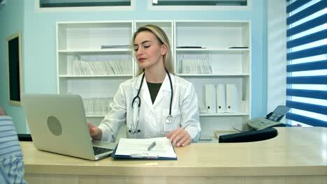 Smiling-nurse-with-laptop-scheduling-appointment-for-male-patient-at-reception