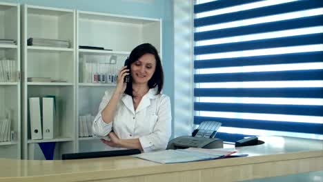 Sonriente-mujer-enfermera-llamada-contestador-en-el-mostrador-de-recepción