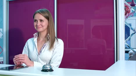 Friendly-young-woman-at-the-hotel-reception-desk