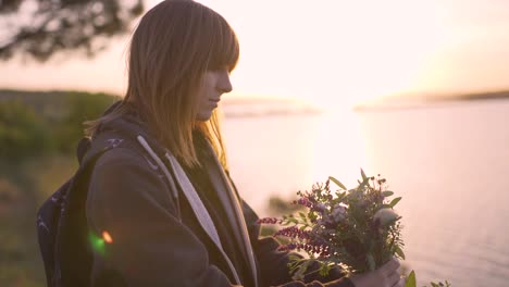 beautiful-young-woman-with-a-bouquet-of-wildflowers-on-the-coast-at-sunset