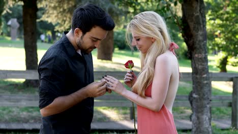 Proposal-of-marriage-at-the-park:-man-kneels-in-front-of-his-future-bride