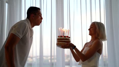 Hombre-joven-sople-velas-de-pastel-de-cumpleaños