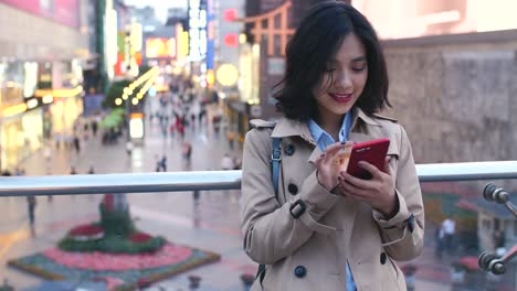 Joven-mujer-asiática-usando-teléfono-inteligente-en-la-ciudad