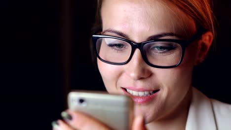 En-la-cabeza-de-una-señora-bastante-joven-en-vasos-con-smartphone-tocar-pantalla-navegando-navegando-por-Internet-y-sonriendo.-Concepto-moderno-de-gadgets-y-de-la-juventud.