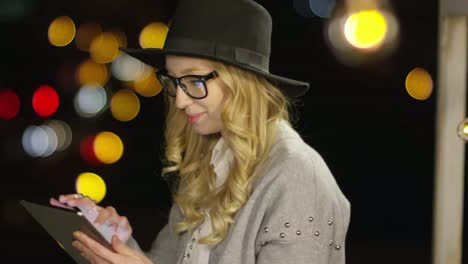 Blonde-Frau-lächelnd-und-mit-Tablet-in-Night-City