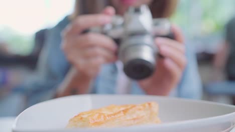 Comida-bloguera-mujer-asiática-con-cámara-para-foto-postre,-pan-y-bebida-sentado-en-la-mesa-de-café.-Estilo-de-vida-mujeres-hermosas-relajación-en-conceptos-de-cafetería.