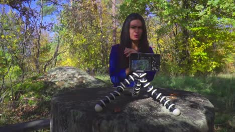 Blogger-young-woman-sitting-next-to-camera-on-the-nature-talking-and-gesturing-slow-motion