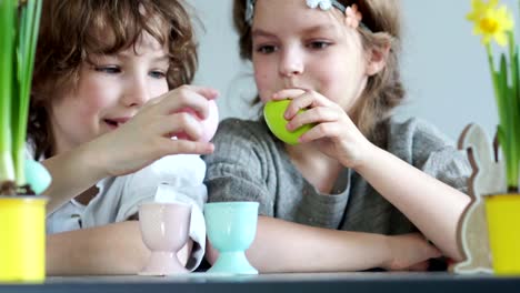 Close-portrait-of-a-boy-and-girl-with-paints-and-brushes.-Children's-Easter-creativity.-Brother-and-sister-decorate-Easter-eggs-and-laugh-merrily