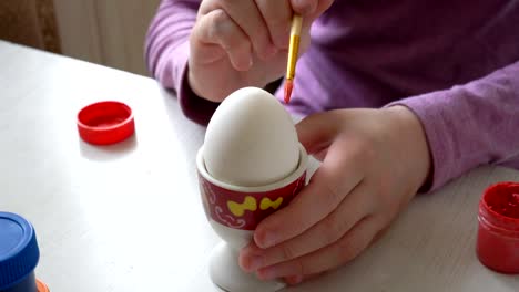 Close-up,-white-Easter-egg-stands-on-a-stand,-and-the-child-draws-on-it-with-a-brush.-4K.