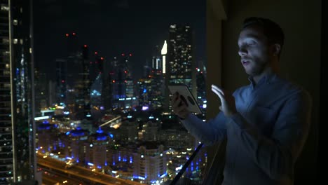 Young-man-using-tablet-to-speak-and-communicate-with-skyscraper-view-background