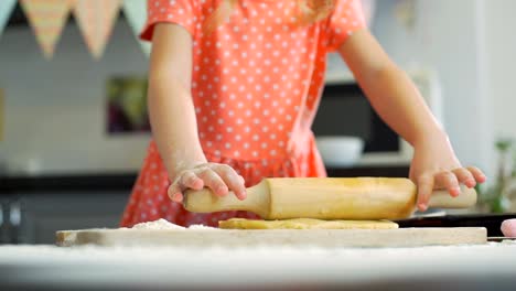 Chica-pequeña-rodando-la-masa-para-las-galletas