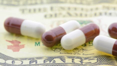 Pills-on-money---pan-across-the-'dollars'-part-of-the-bill-towards-an-open-pill-bottle-on-the-right