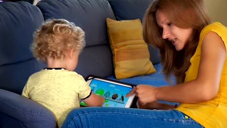 niña-de-niño-con-la-madre-jugando-en-la-computadora-de-la-tableta.