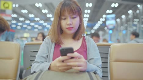 Slow-motion---Asian-woman-using-smartphone-while-sitting-in-international-airport.