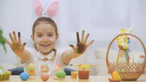 La-pequeña-chica-linda-y-adorable-está-sonriendo-sinceramente.-La-chica-le-está-mostrando-su-pequeño-piso-de-manos.-Concepto-vacaciones-de-Pascua.