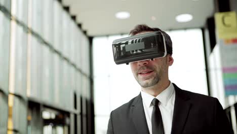 Medium-shot-of-modern-businessman-in-formal-suit-and-VR-goggles-walking-along-business-center-hall-and-taking-part-in-video-conference