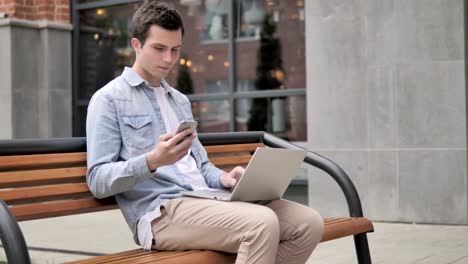 Junge-Mann-sitzt-auf-Bank,-während-er-online-arbeitet