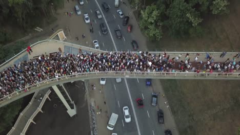 Eine-Menschenmenge-auf-einer-Fußgängerbrücke-ist-am-Frühlingsabend-zu-sehen.-Luftaufnahme.-Eine-neue-Fahrrad-Fußgängerbrücke-im-Zentrum-der-Hauptstadt-der-Ukraine,-der-Stadt-Kiew.-Ausflüge-und-Spaziergänge-für-Touristen