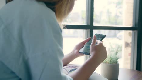 Geschäftspfreundin-Asiens,-die-Smartphone-zum-Sprechen,-Lesen-und-Texten-benutzen,-während-sie-im-Café-am-Tisch-sitzen.-Lifestyle-Smart-beautiful-Frauen-arbeiten-in-Coffeeshop-Konzepte.