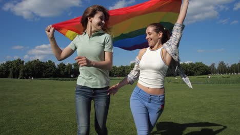 Fröhliches-schwules-Paar-mit-Stolz-Flagge-läuft-im-Freien