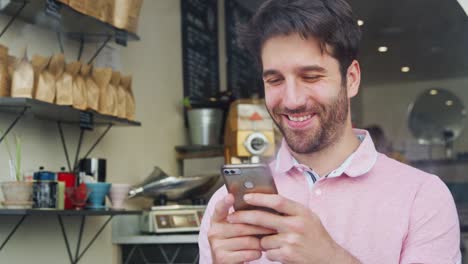 Junger-Mann-in-Coffee-Shop-Blick-auf-Handy