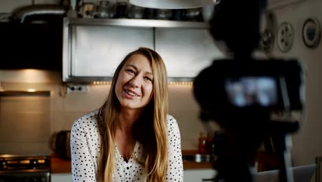 Happy-young-beautiful-food-blogger-woman-filming-new-vlog-video-with-professional-camera-in-the-kitchen-slow-motion.