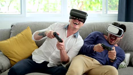 Pareja-gay-relajándose-en-el-sofá-jugando-juegos-de-realidad-virtual.-Emocionante-estado-de-ánimo.-Estado-de-ánimo-muy-emocionante.