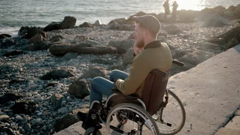 Disabled-man-talking-on-mobile-on-the-shore