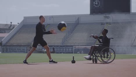 Atleta-en-silla-de-ruedas-y-entrenador-lanzando-pelota-de-medicina