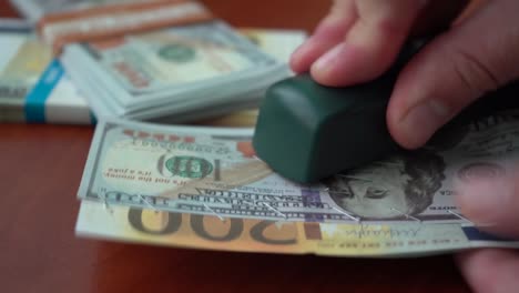 The-stapler-fastens-the-dollar-and-euro-notes-with-iron-clips.-Stapler-with-paper-clips-on-the-background-of-banknotes.-Counterfeit-money