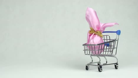 Mano-del-hombre-pone-un-huevo-de-Pascua-regalo-rosa-en-un-fondo-blanco-cesta-de-la-compra,-espacio-de-copia,-supermercado-concepto