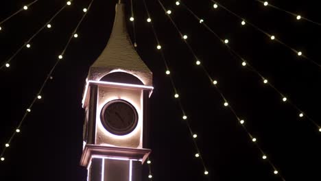 Clock-tower-decorated-with-Christmas-lights,-bulb-garlands-on-city-square-New-Year-market.-Camera-flies-around-decorative-Big-Ben-on-Christmas-Eve.-Time-and-holidays-concepts