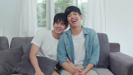 Portrait-Young-Asian-Gay-couple-feeling-happy-smiling-at-home.-Asian-LGBTQ-men-relax-toothy-smile-looking-to-camera-while-lying-on-sofa-in-living-room-at-home-in-the-morning-concept.