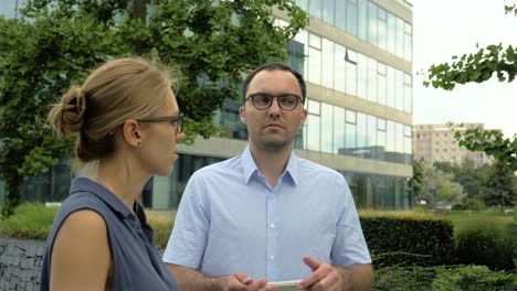 Business-man-and-woman-talking-standing-near-office-building.-Man-listening