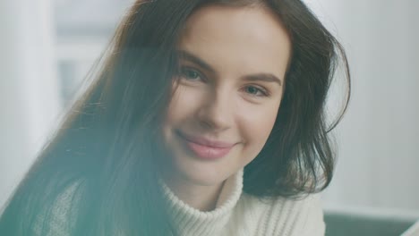 Beautiful-Young-Woman-Using-Smartphone-Happily,-while-Sitting-on-the-Chair.-Sensual-Girl-Wearing-Knitted-Sweater-Surfs-Internet,-Posts-On-Social-Media,-Sharing-Picture-while-Relaxing-in-Cozy-Apartment