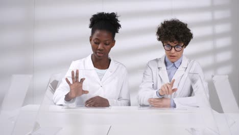 Two-Female-Scientists-Working-on-Futuristic-Touchscreens-Together-in-Lab