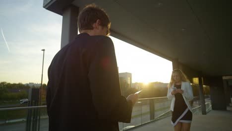 CLOSE-UP-Handsome-yuppie-smiles-after-woman-looking-at-smartphone-bumps-into-him