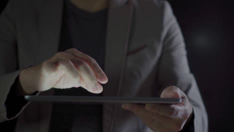 4K-Video-close-up-man-hand-in-suit-using-tablet-with-black-background.