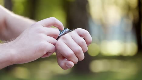 Vista-de-cerca-de-la-mano-masculina-con-moderno-dispositivo-de-reloj-inteligente-fuera-de-la-pantalla-táctil-negra.-Comprobación-de-la-notificación-en-línea.-Medición-de-la-distancia,-frecuencia-cardíaca.-atención-sanitaria