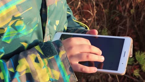 Close-up-of-a-boy's-hand-working-on-a-tablet-in-the-street.