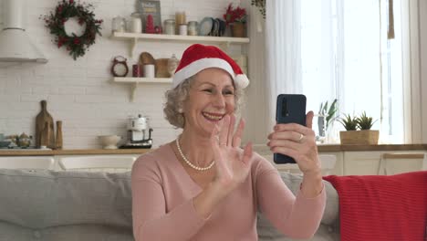 Cheerful-old-woman-in-red-hat-smiles-conducting-video-call